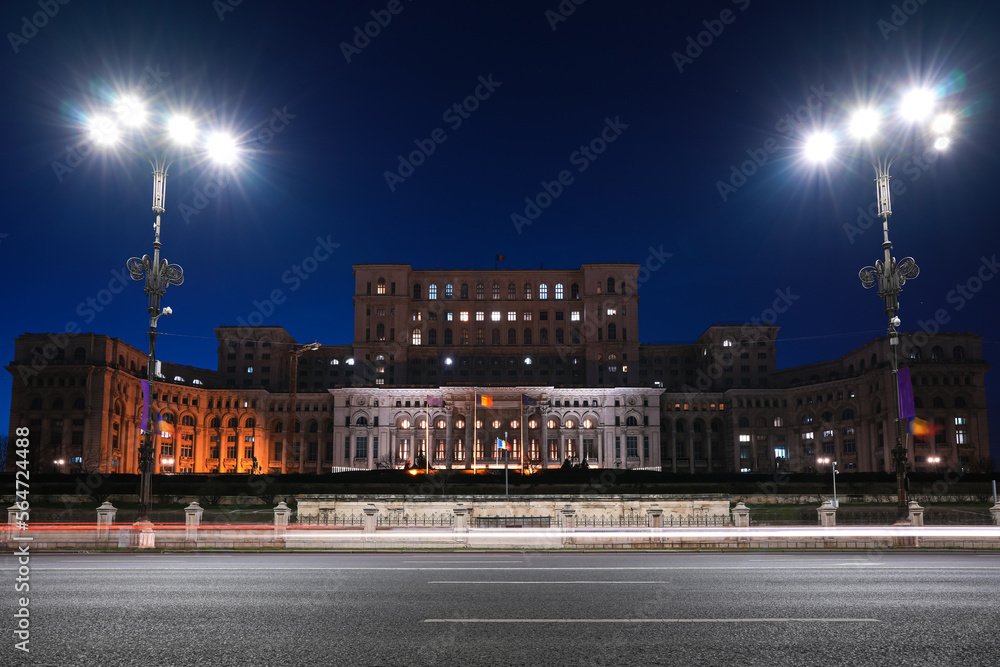 Obraz premium Night in Bucharest. Night rush hour traffic long exposure on the boulevard street in front of Palace of Parliament landmark building from Romania.