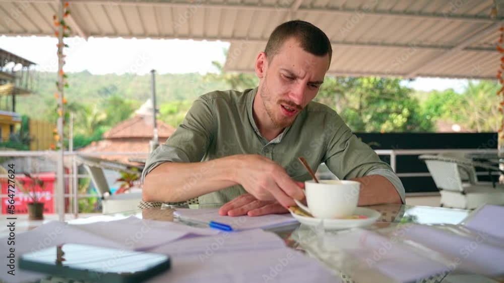 Man takes notes in a notebook, takes a sip of coffee and looks into the distance Man takes notes in a notebook, takes a sip of coffee and looks into the distance