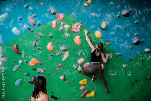 Woman hanging from rock climbing wall