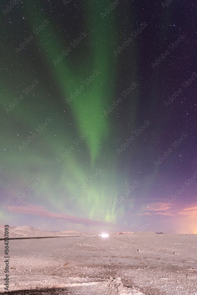 imagen nocturna de un paisaje nevado con una aurora boreal iluminando el cielo de color verde y las estrellas de fondo