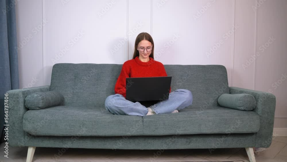 woman with glasses sitting on sofa legs crossed folded work remote use of laptop. using laptop at home, looking at screen, reading or writing emails, sitting on couch, serious student doing homework, woman with glasses sitting on sofa legs crossed folded work remote use of laptop. using laptop at home, looking at screen, reading or writing emails, sitting on couch, serious student doing homework,