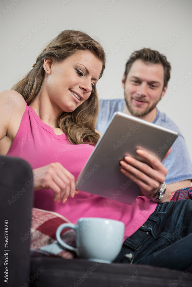 Couple using digital tablet in living room, Munich, Bavaria, Germany Couple using digital tablet in living room, Munich, Bavaria, Germany