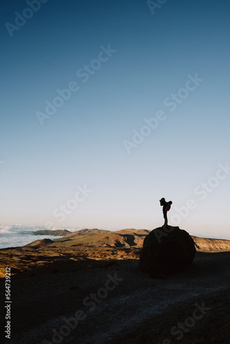 Silhouette of a male hiker taking photo of volcanic landscape, vertica