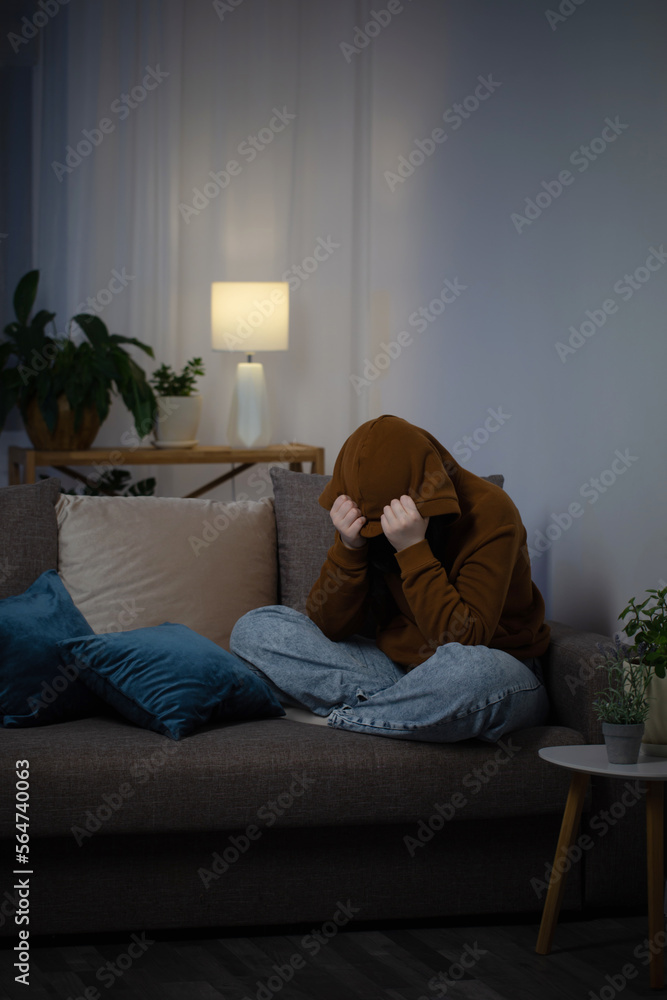 sad teenager girl sitting on couch indoor at night sad teenager girl sitting on couch indoor at night