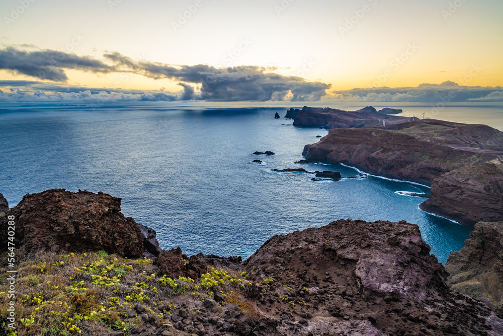 Panoramic view from a steep cliff over the seascape and along the rugged foothills of Madeira coast at dawn. Ponta do Bode, Madeira Island, Portugal, Europe.