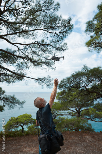 An adult male takes a quadcopter on his arm after taking a photo-video of a picturesque seascape in the Blue Abyss Lagoon