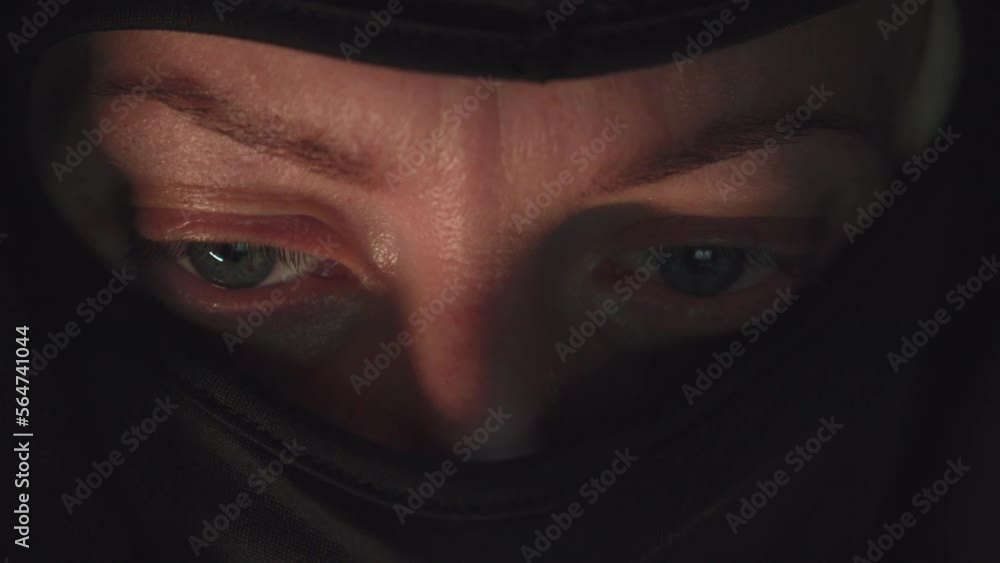 Eyes of thief in mask looking at computer screen in dark room Eyes of thief in mask looking at computer screen in dark room