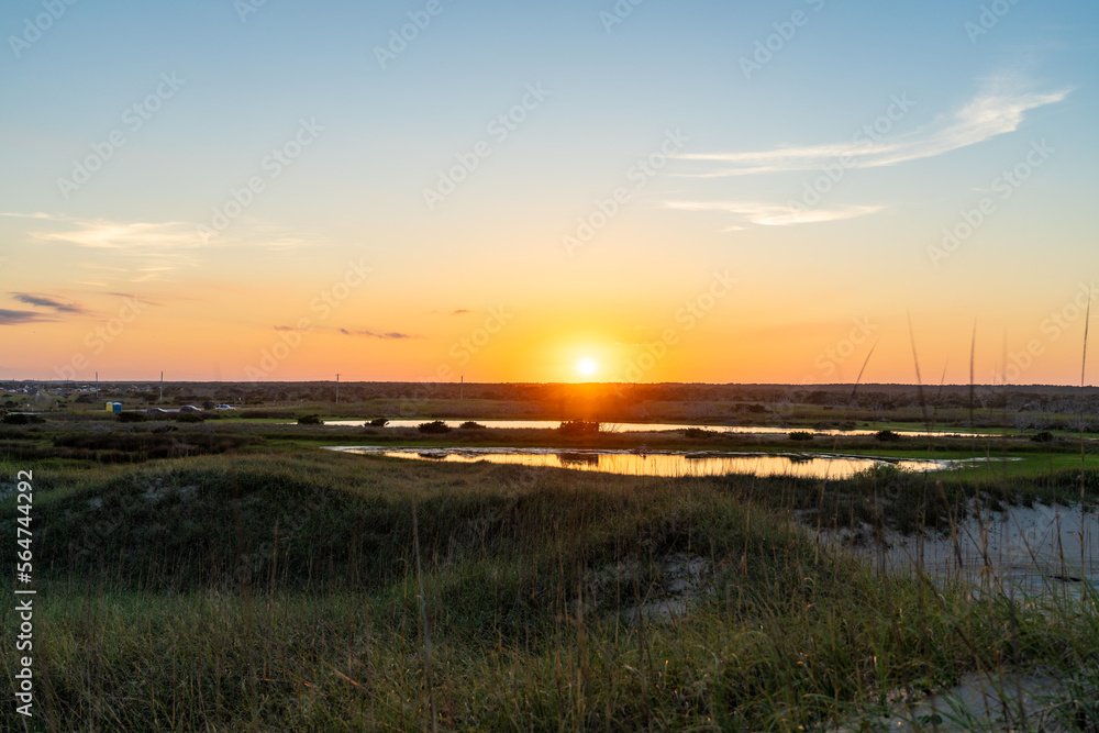 Obraz premium View of the Sunset on Hatteras Island Seen across a Tidal Marsh Near the Beach