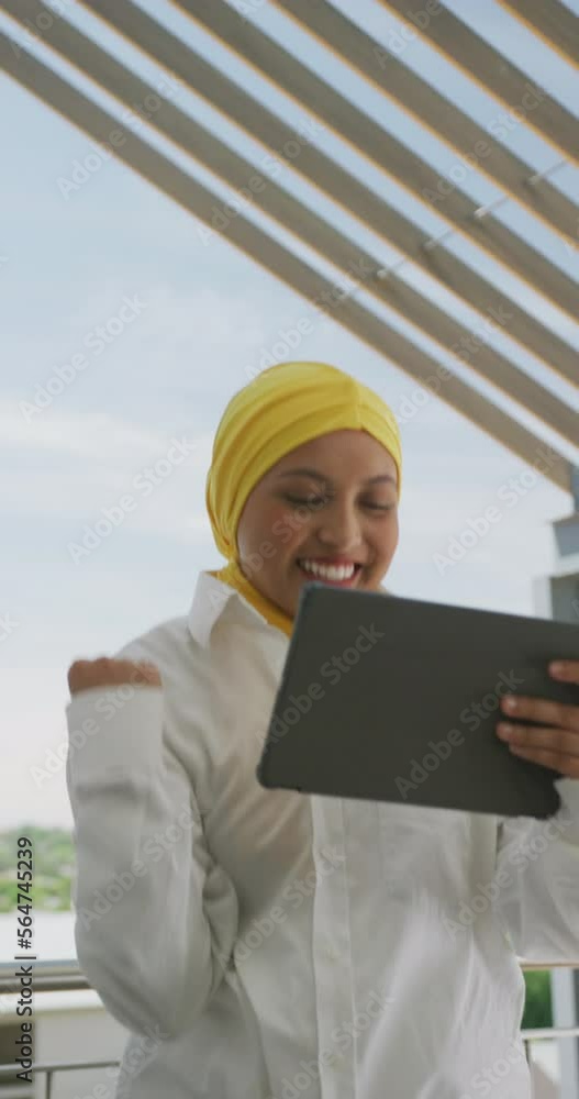 Vertical video of happy biracial businesswoman celebrationg and using tablet at office Vertical video of happy biracial businesswoman celebrationg and using tablet at office