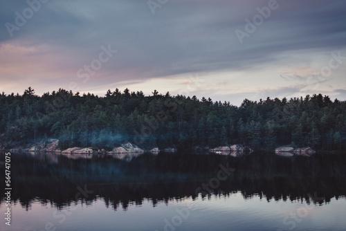 Calm Lake At Dusk With A Canoe Crossing Over photo