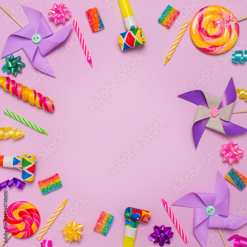 Birthday children party background with candels sweets and party attributes on violet surface.