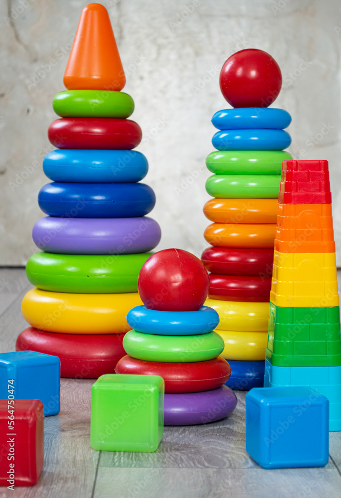Children's educational toys. Colorful pyramids and cubes standing on the floor, close up Children's educational toys. Colorful pyramids and cubes standing on the floor, close up