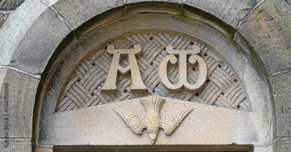 Alpha and Omega with a dove  beneath on top of a door of a Roman Catholic church