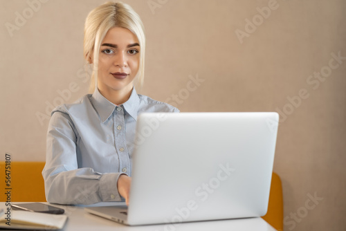 Young girl student or office worker at the workplace behind a laptop.