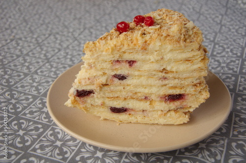 Piece of Napoleon cake on a beige plate close-up.