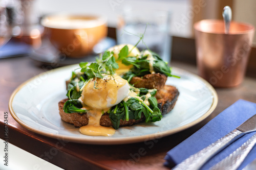 Healthy balanced breakfast with poached eggs, spinach and hollandaise sauce on toasted sourdough bread