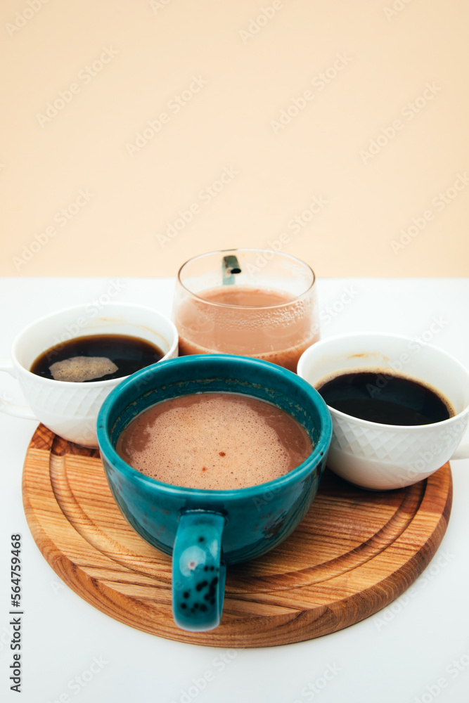 A set of mugs with different coffees on a wooden tray. Front view A set of mugs with different coffees on a wooden tray. Front view