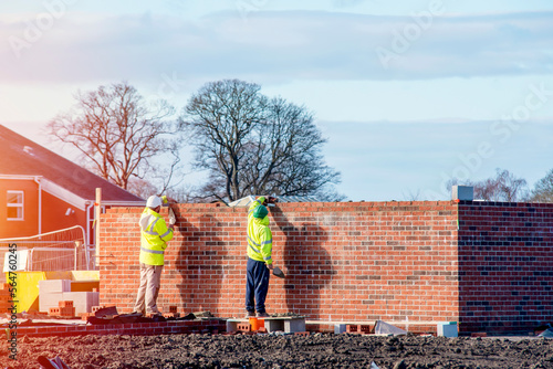 Industrial bricklayer laying bricks on cement mix on construction site