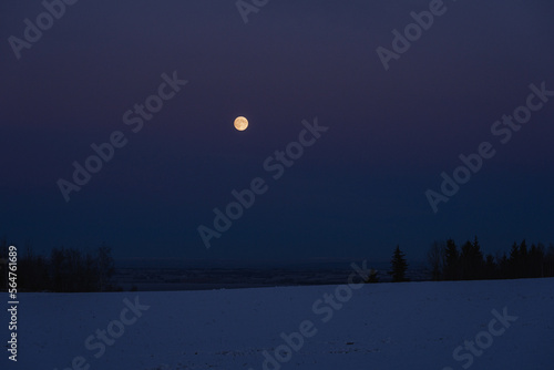 The full moon above Lake Mj  sa in winter.