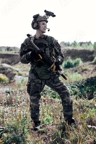 caucasian european army soldier outdoors, standing with assault rifle and machine gun, posing at camera, looking at side, wearing military uniform. in nature. portrait