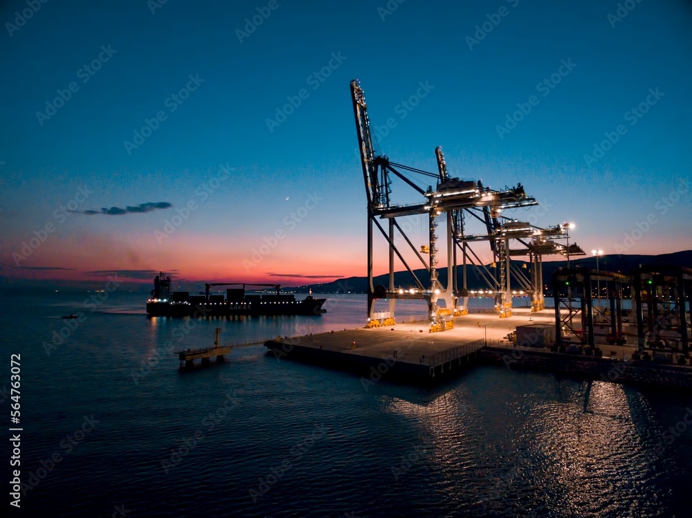 Fototapeta premium sunset drone photo of giant cranes in harbor