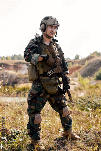 chinese equipped camouflaged soldier with rifle standing and posing outdoors, alone. portrait of young male with weapon looking at side confidently. military forces, defense concept