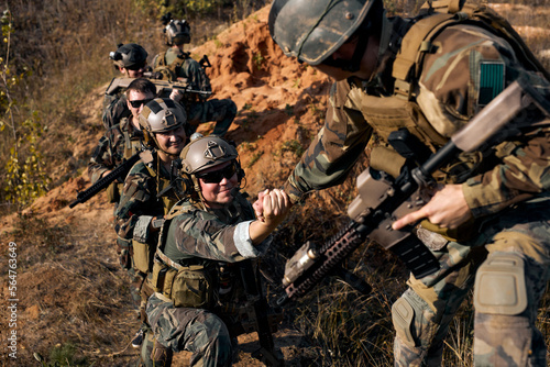 brave command rangers soldiers during the military operation. soldiers climbing on mountain, one of them giving hand and helping to climb. Help, support, assistance in a dangerous situation