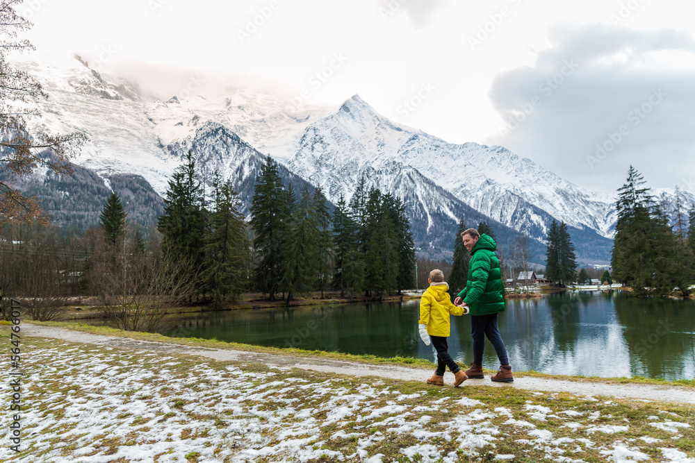 Father and son togethe walking at Gaillands lake in Chamonix, french alps.Clouses green and yellow.