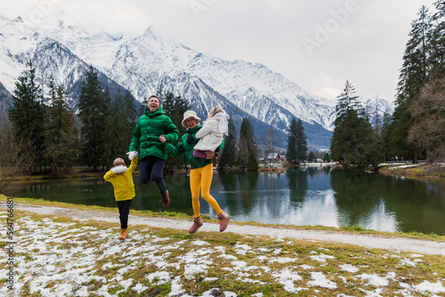 Happy family jumping and having fun on holiday at Gaillands lake in Chamonix, french alps.