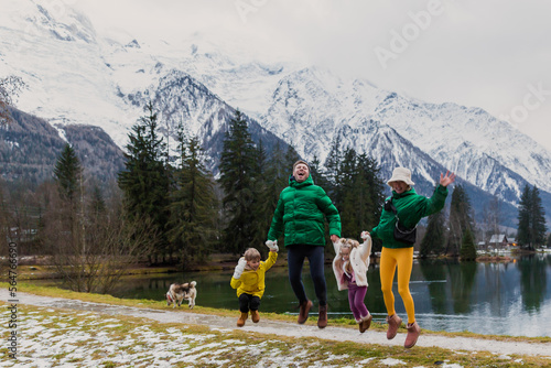 Happy family jumping and having fun on holiday at Gaillands lake in Chamonix, french alps.