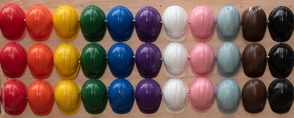 Colorful helmets as a protection for head for workers.  Construction industry and equipment for builder. Rainbow and lgbt at work. Banner. - obrazy, fototapety, plakaty 