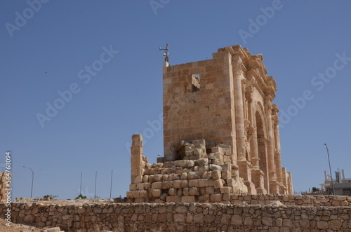 Sunny temples, arches, the Nymphaeum, stone ornaments, columns and column bases on the ruins of the city of Jerash in Jordan.