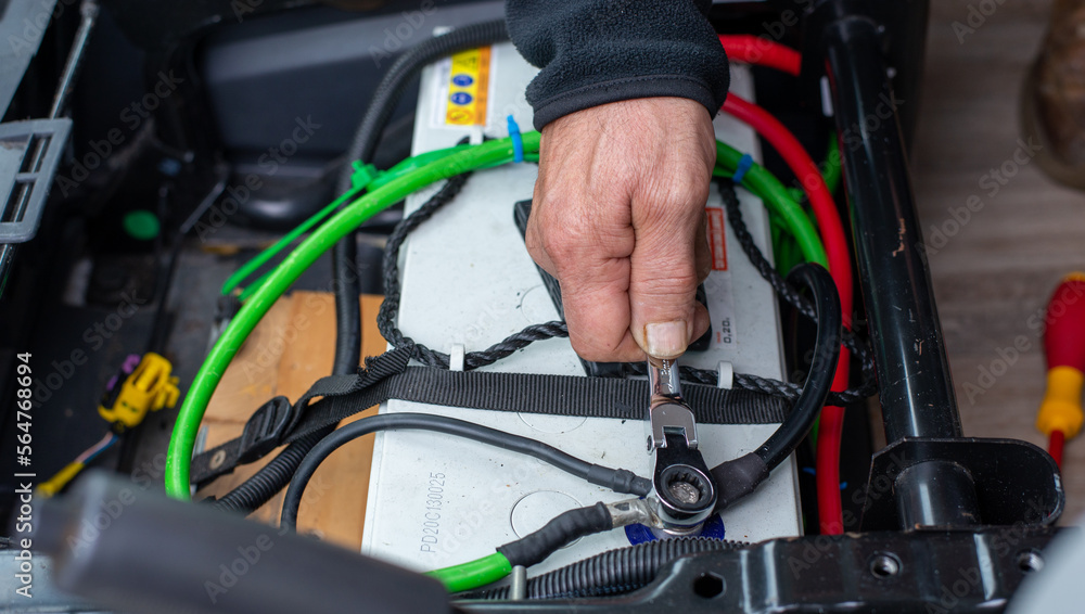 man hand servicing vehicle, tightening battery terminal with tool in hand. man hand servicing vehicle, tightening battery terminal with tool in hand.