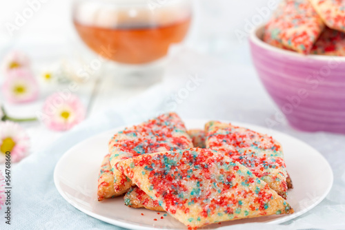Homemade cookies with colored sugar with tea on a light wooden background. The concept of breakfast.
