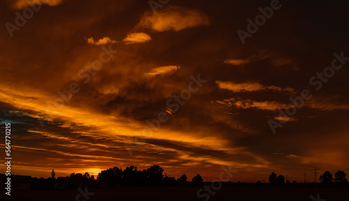 Beautiful sunset with a dramatic sky and overland high voltage lines near Tabertshausen, Bavaria, Germany