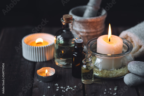 Spa setting with essential oil  candle  sea salt  pebbles  towel on dark wooden background. Massage  aromatherapy. Natural organic ingredients for relaxation  detention. Wellness in salon concept