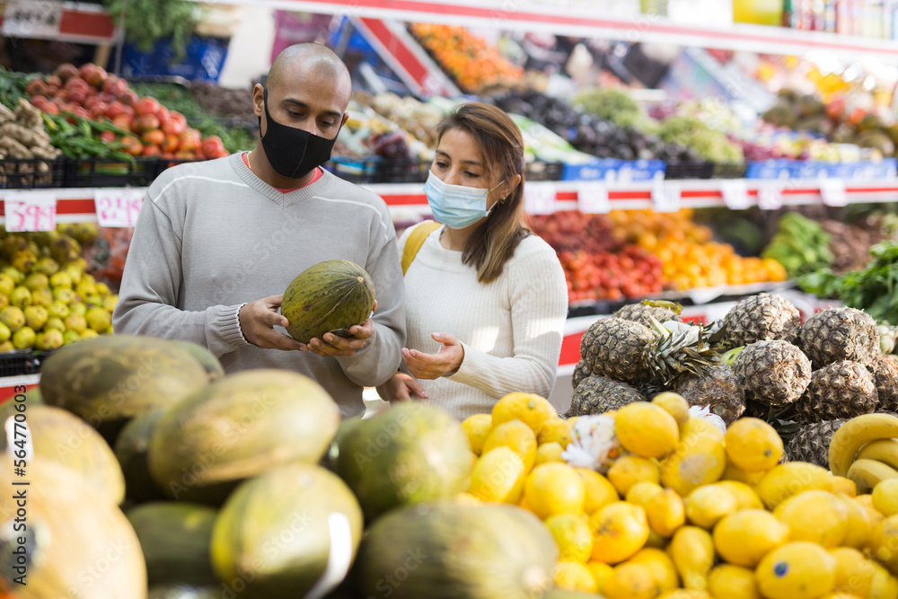 Portrait of latin couple wearing medical masks in supermarket during COVID-19 quarantine