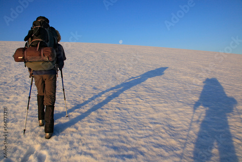Hikers crossing Drangajï¾škull ice cap, Hornstrandir Peninsula, Iceland with simultaneous sunrise shadows and full moon