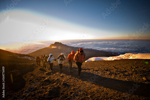 A team of hikers approach the summit of Mt. Kilimanjaro at sunrise after trekking six hours through the night. photo