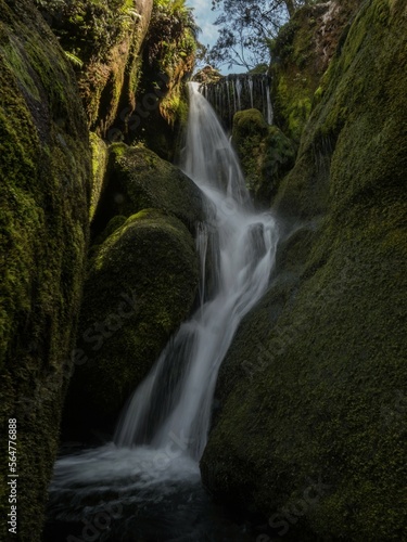 Long exposure of small freshwater river stream waterfall flowing through mossy rocks creek in Abel Tasman National Park