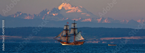 Nineteenth century replica ship, Hawaiian Chieftain, sets sail in Penn Cove, Washington, USA at sunset with Mount Baker in the distance. photo