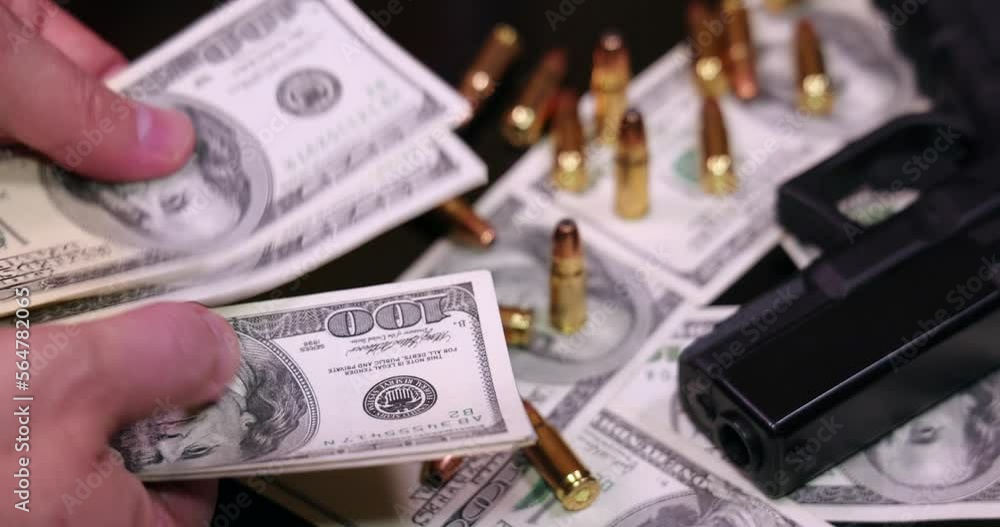 Gun and bullets on dollar banknotes background, closeup shot. Criminal money. Black money and protection, mafia and corruption concept. Male hands count money or pay, slow motion Gun and bullets on dollar banknotes background, closeup shot. Criminal money. Black money and protection, mafia and corruption concept. Male hands count money or pay, slow motion
