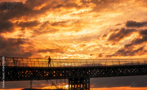 view of solo male person on a bridge at sunset time with beautiful clouds on sky