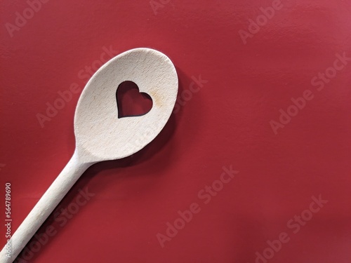 wooden spoon with heart shape inside on burgundy background
