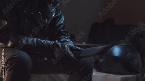 Person wearing black leather gloves takes out huge knife from a duffle bag photo