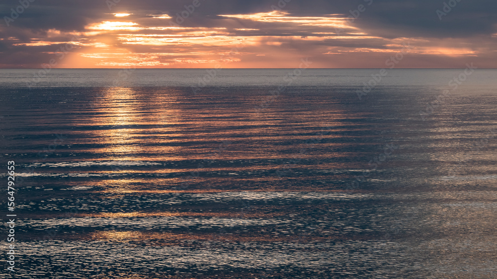 Fototapeta premium A vivid gold and orange sunset reflects across Lake Michigan. 