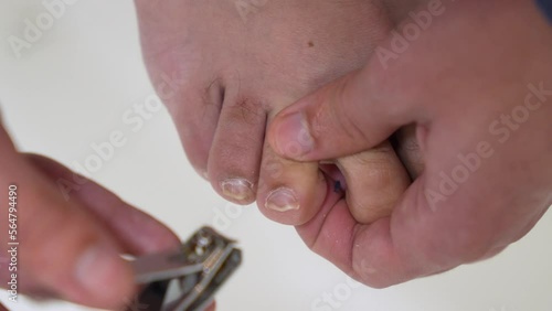 A guy cuts his toenails with pliers on a white background