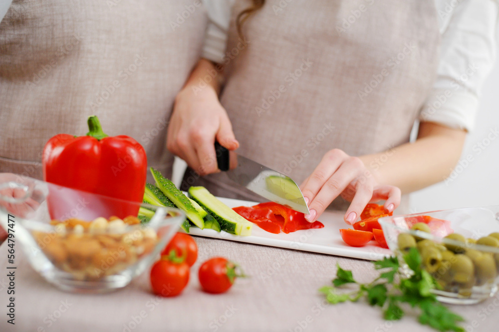 Close up cropped image of cutting board and couple cutting vegetables in the kitchen together, preparing food meal at home. Vegetarian healthy food Couple preparing a meal cut bell pepper Close up cropped image of cutting board and couple cutting vegetables in the kitchen together, preparing food meal at home. Vegetarian healthy food Couple preparing a meal cut bell pepper