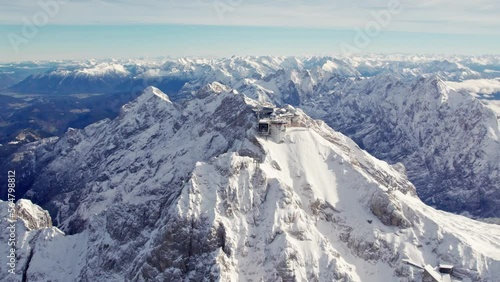 aerial orbiting around the summit of zugspitze a snowy mountain peak in the alps with an impressive building on top