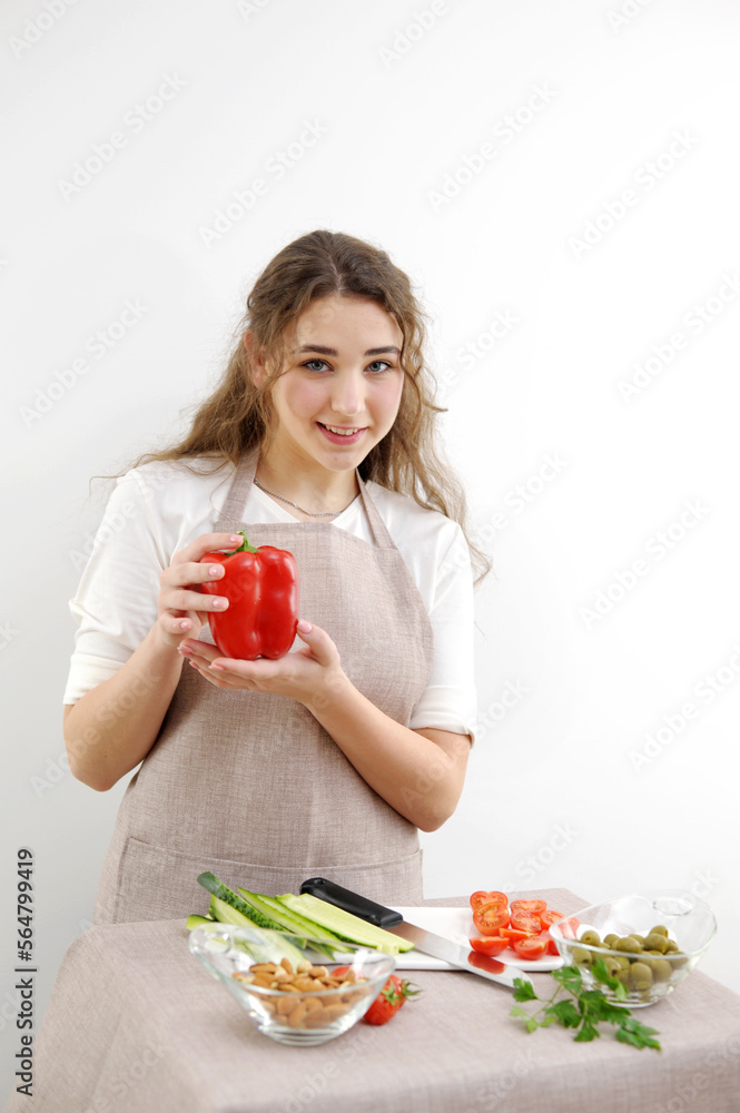 Smiling brunette woman holding red bell pepper while standing with hand on hip Green vegan salad with mixed green leaves Green salad with tomatoes and fresh vegetables Smiling brunette woman holding red bell pepper while standing with hand on hip Green vegan salad with mixed green leaves Green salad with tomatoes and fresh vegetables